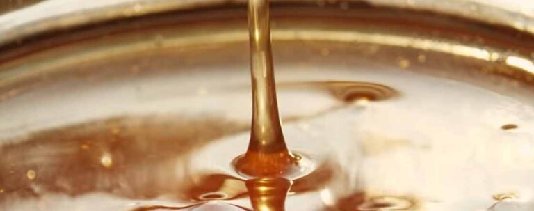 Hönig der goldene Saft läuft vom Honiglöffel